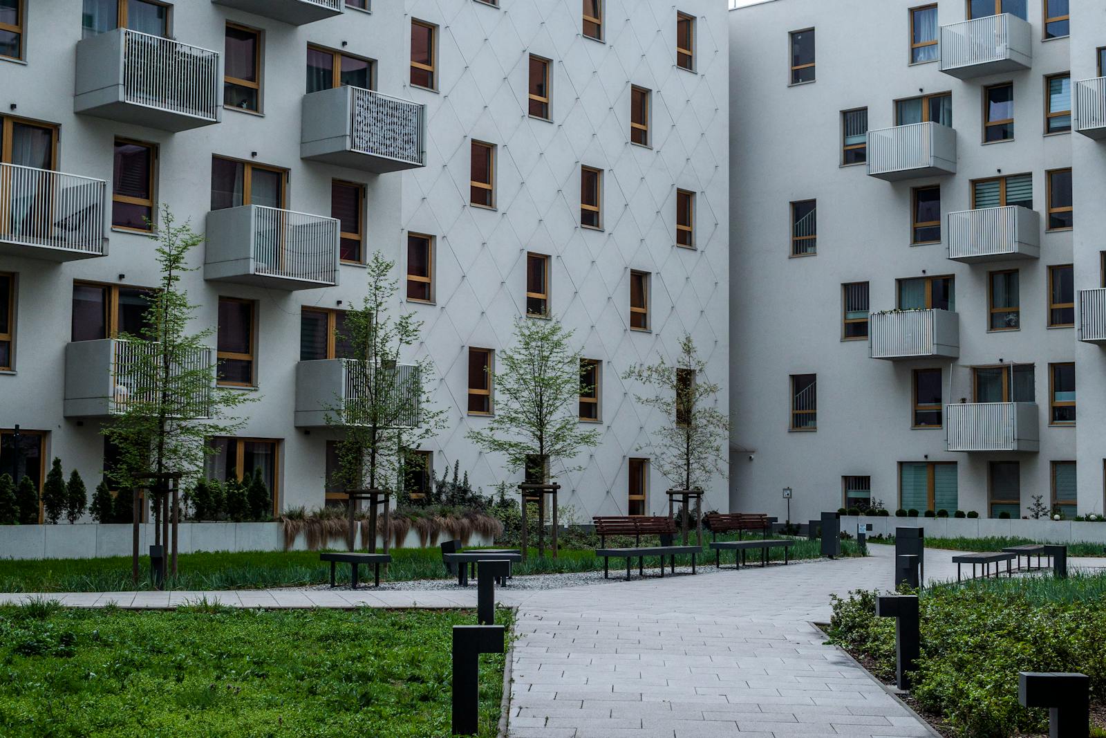 Arkitektonisk detalj från bostadsgård med balkonger och mjuka färger.